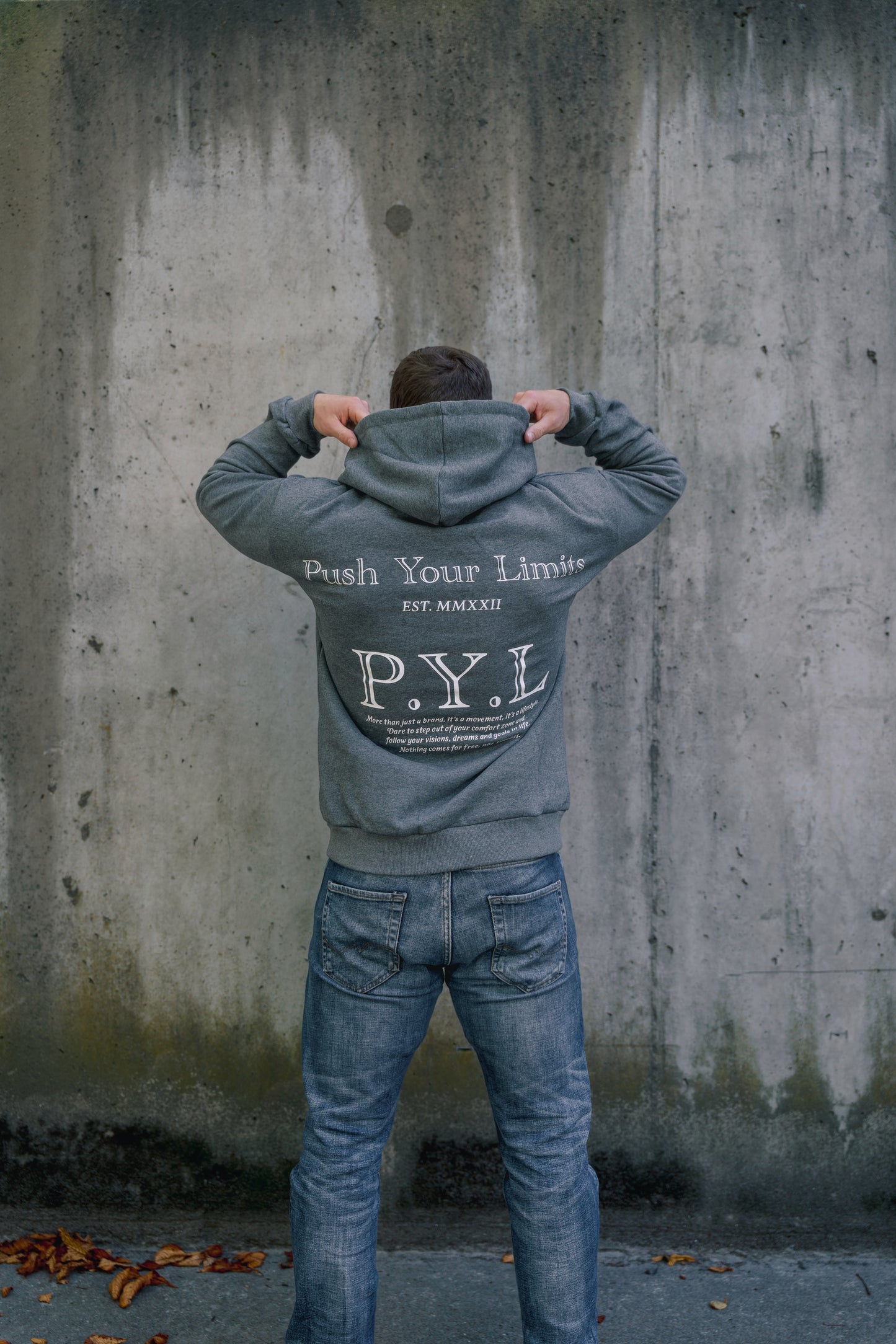 Person wearing a hoodie with 'Push Your Limits' text against a concrete wall.