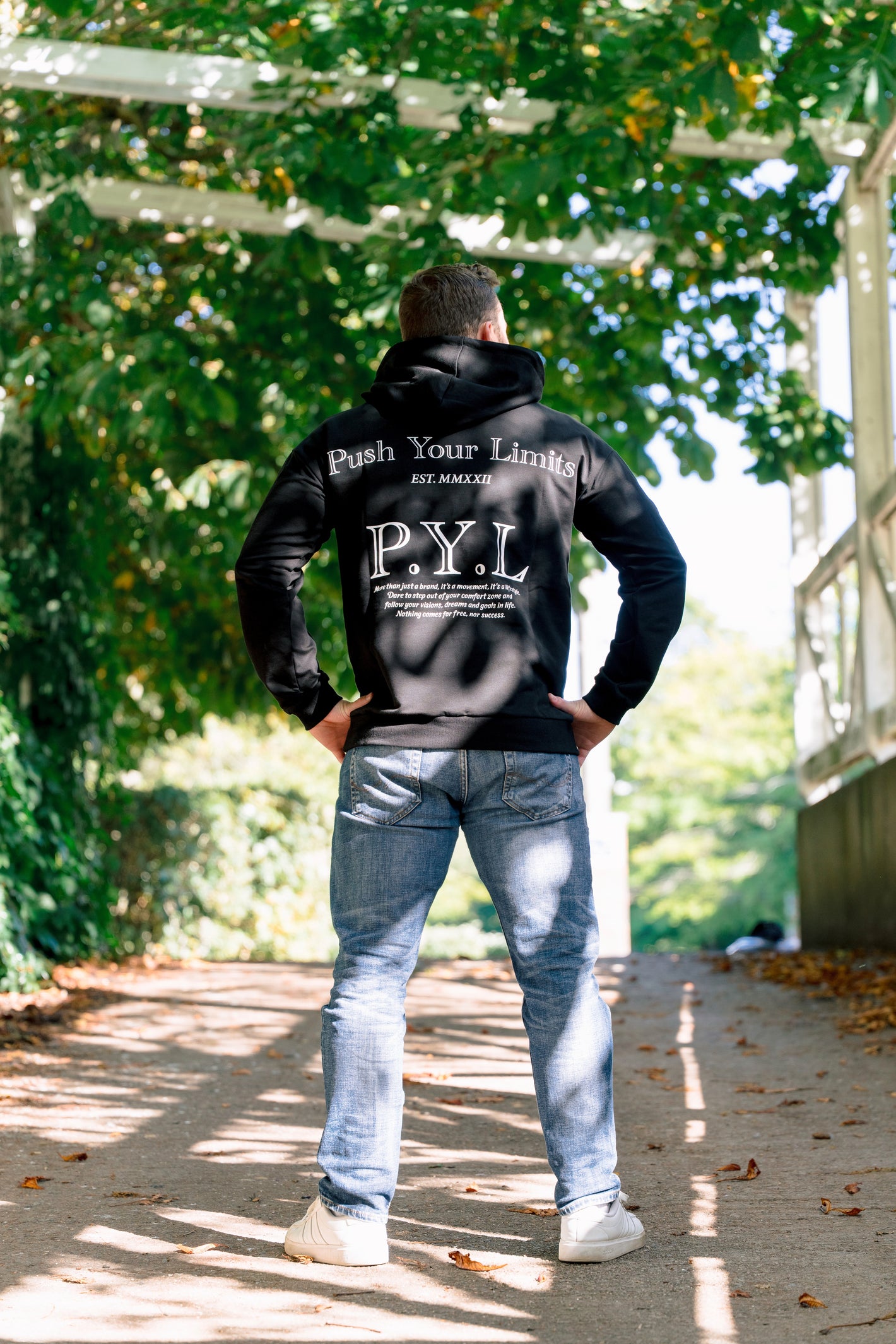 Person wearing a black hoodie with 'P.Y.L' branding in an outdoor setting